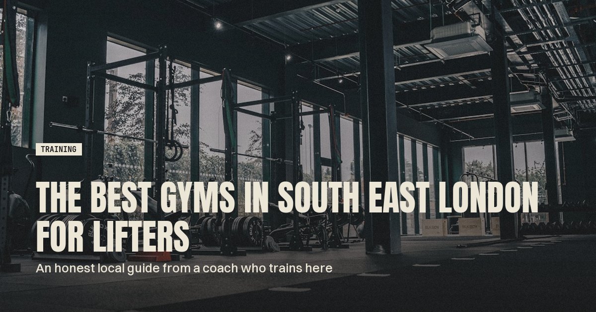 Dark industrial gym floor with squat racks, benches and stacked bumper plates